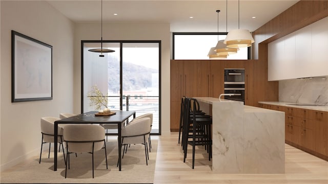 kitchen featuring light wood-type flooring, a kitchen island, decorative light fixtures, and decorative backsplash