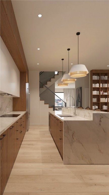 kitchen featuring light wood-type flooring, stainless steel refrigerator, backsplash, sink, and hanging light fixtures