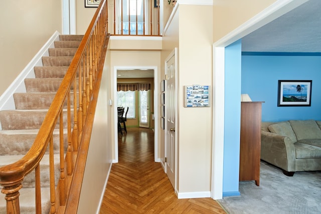 stairway featuring ornamental molding and parquet flooring