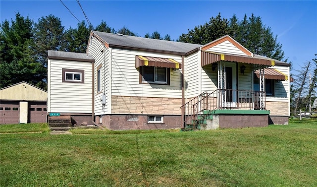 bungalow-style home with a front lawn, an outbuilding, and a garage