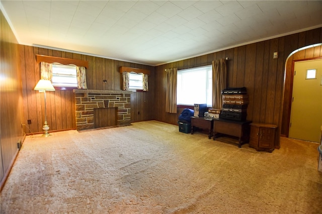 unfurnished living room with wood walls, a fireplace, and carpet floors