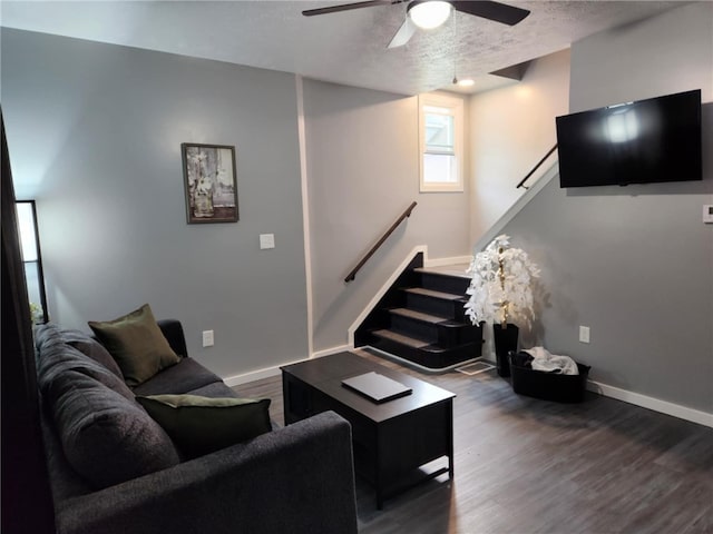 living room with dark hardwood / wood-style flooring, ceiling fan, and a textured ceiling