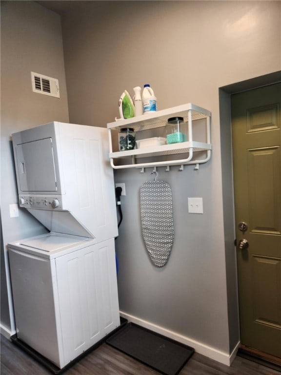 laundry room with dark hardwood / wood-style floors and stacked washer / dryer