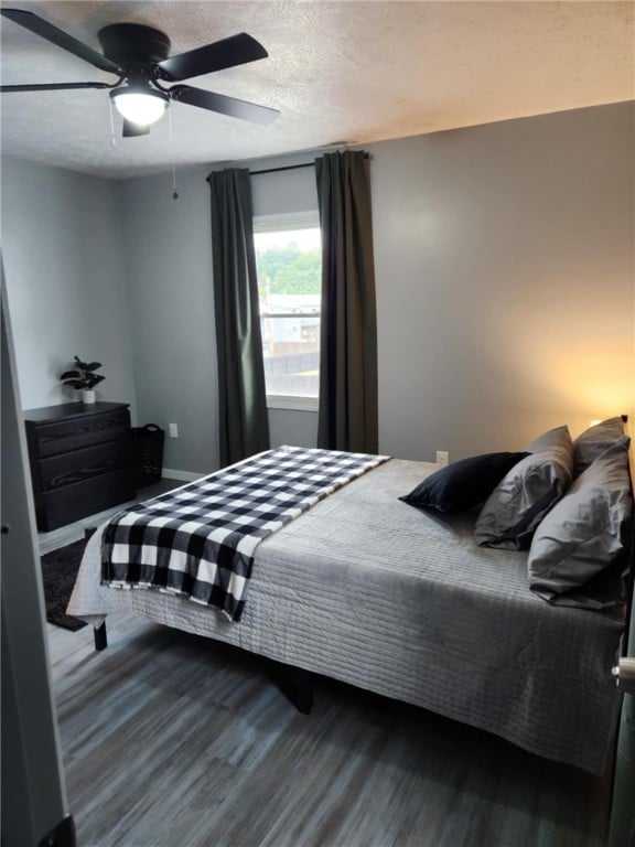 bedroom with a textured ceiling, ceiling fan, and hardwood / wood-style flooring