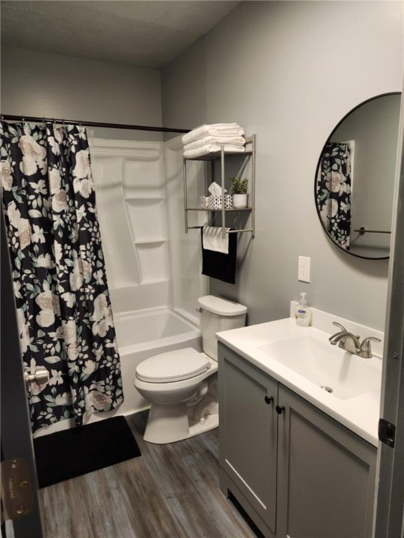 full bathroom with shower / bath combo, hardwood / wood-style floors, toilet, vanity, and a textured ceiling