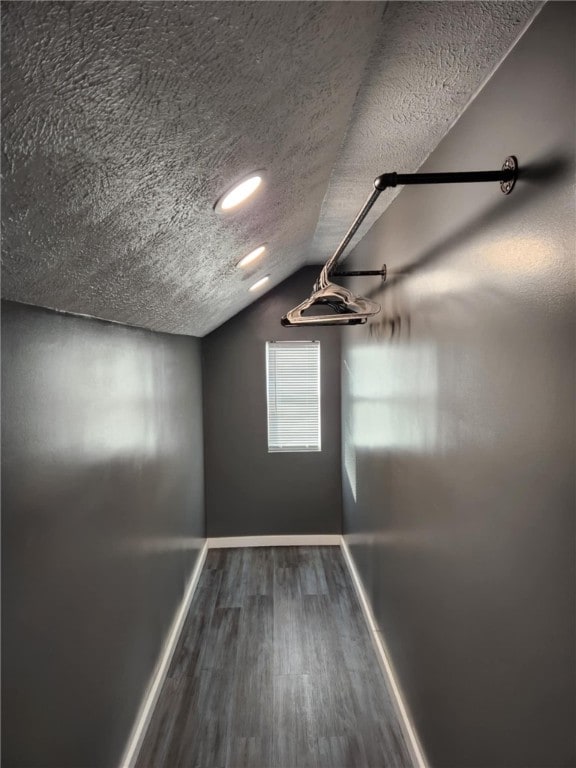 additional living space with a textured ceiling, vaulted ceiling, and hardwood / wood-style flooring