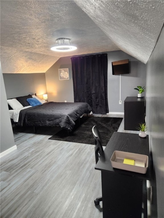 bedroom with lofted ceiling, hardwood / wood-style floors, and a textured ceiling