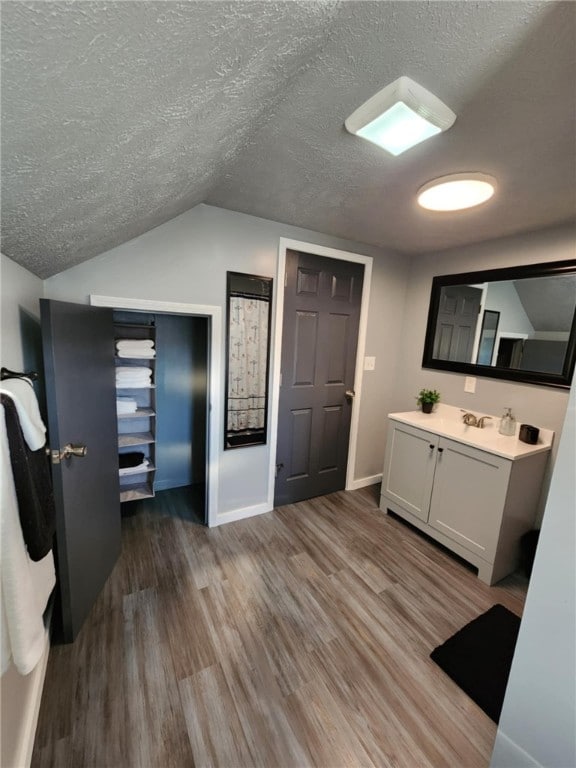 kitchen with hardwood / wood-style floors, a textured ceiling, and vaulted ceiling