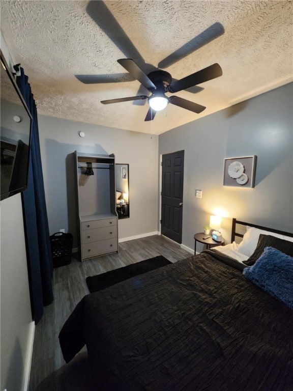 bedroom with a textured ceiling, hardwood / wood-style flooring, and ceiling fan