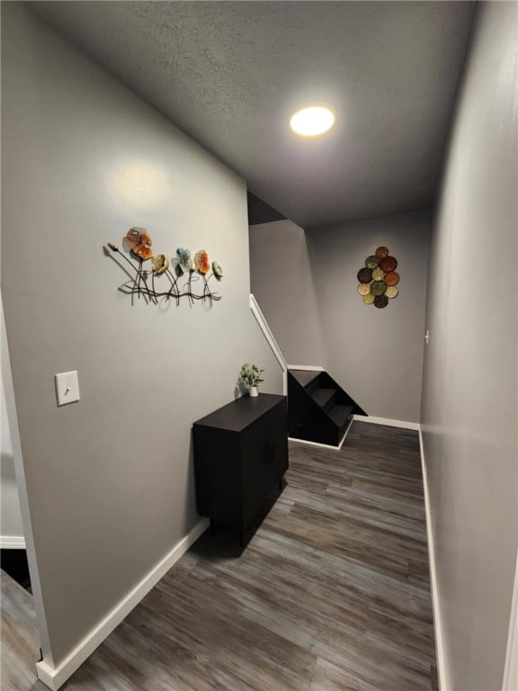 corridor with a textured ceiling and hardwood / wood-style floors