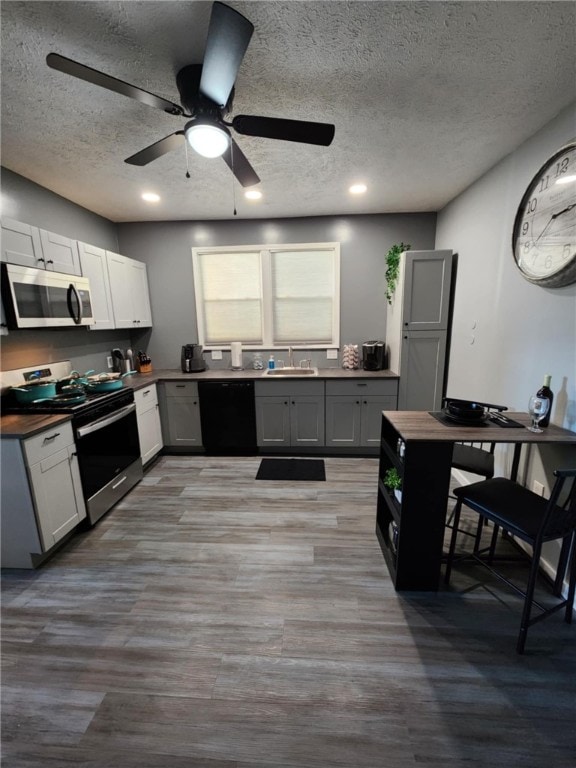 kitchen featuring a textured ceiling, wood-type flooring, sink, ceiling fan, and appliances with stainless steel finishes