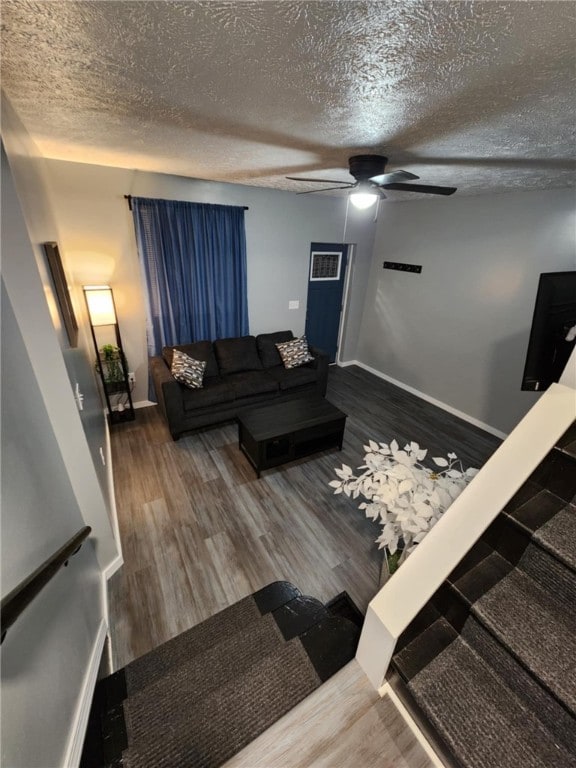 living room featuring hardwood / wood-style floors, ceiling fan, and a textured ceiling