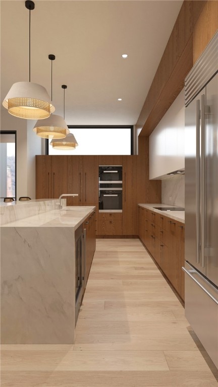 kitchen featuring double oven, stainless steel built in refrigerator, pendant lighting, and light hardwood / wood-style flooring