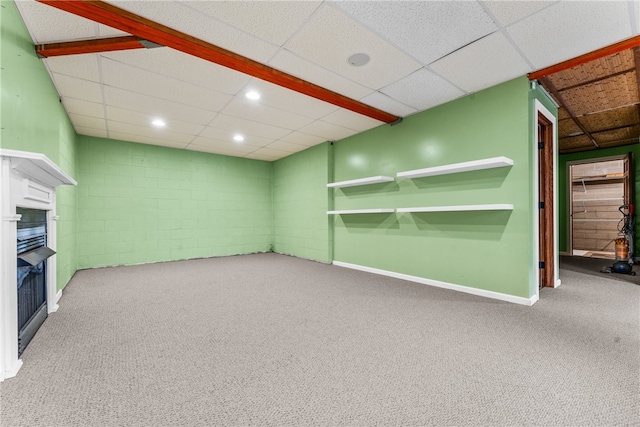 basement with carpet flooring, a paneled ceiling, and a fireplace