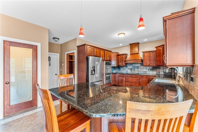 kitchen featuring a breakfast bar area, pendant lighting, custom range hood, and appliances with stainless steel finishes