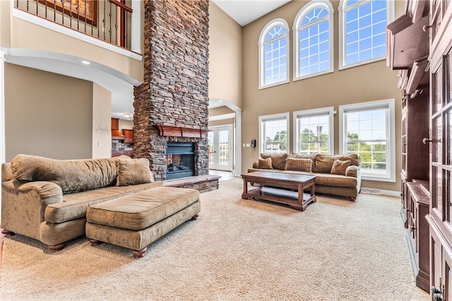 carpeted living room with a stone fireplace and a towering ceiling