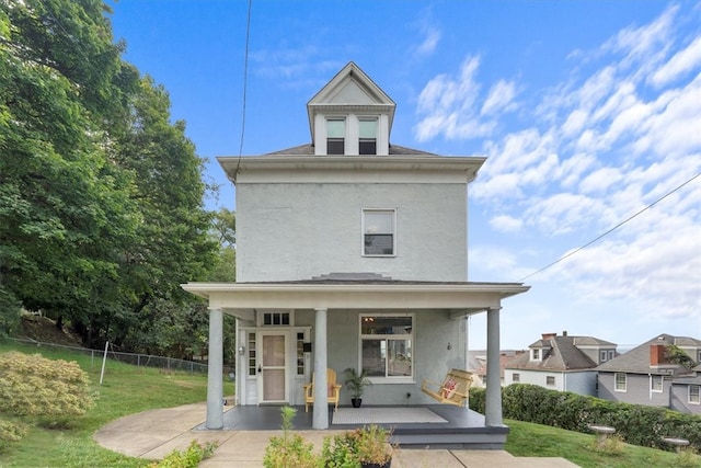 back of property featuring a lawn and covered porch