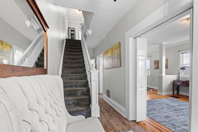 stairs featuring hardwood / wood-style floors and crown molding