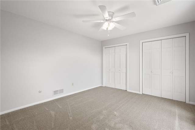 unfurnished bedroom featuring two closets, ceiling fan, and carpet floors