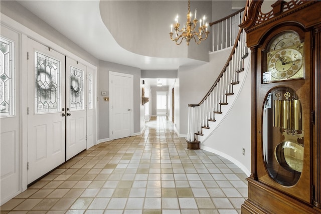 tiled entryway featuring a wealth of natural light, a raised ceiling, and a notable chandelier