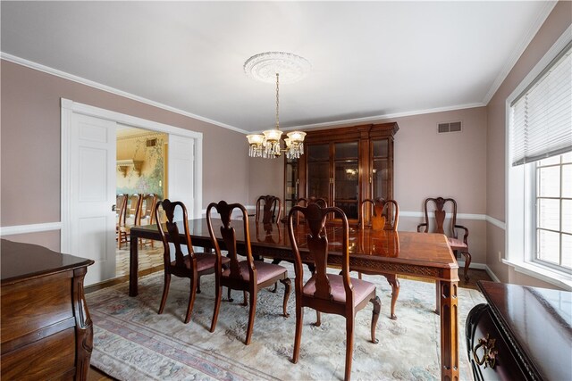 dining space with light hardwood / wood-style flooring, an inviting chandelier, and ornamental molding