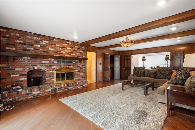 living room with wood walls, hardwood / wood-style floors, beamed ceiling, and a fireplace