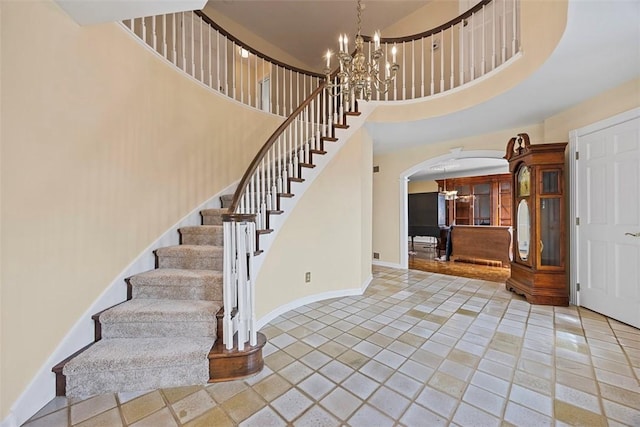 6840 Kevin Dr, Bethel Park, PA 15102 - staircase with a chandelier, arched walkways, a high ceiling, tile patterned floors, and baseboards