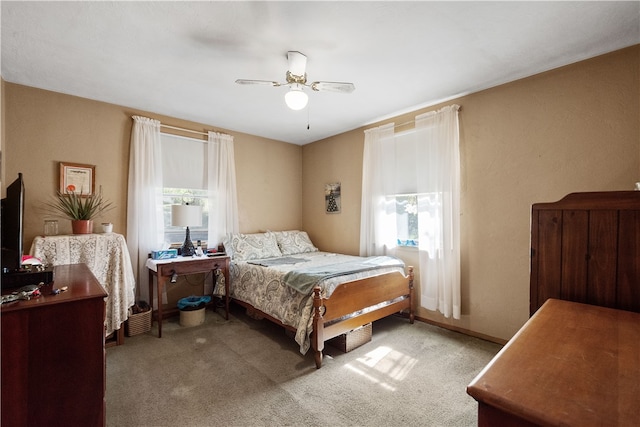 bedroom with multiple windows, light colored carpet, and ceiling fan