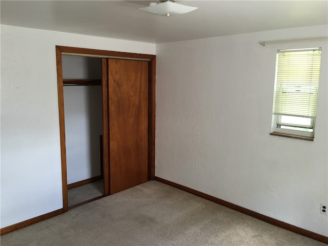 unfurnished bedroom with light carpet and a closet