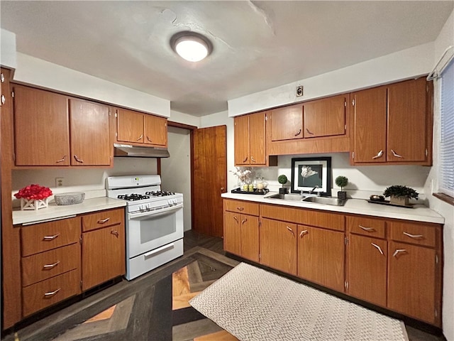 kitchen with white gas range, dark hardwood / wood-style floors, and sink