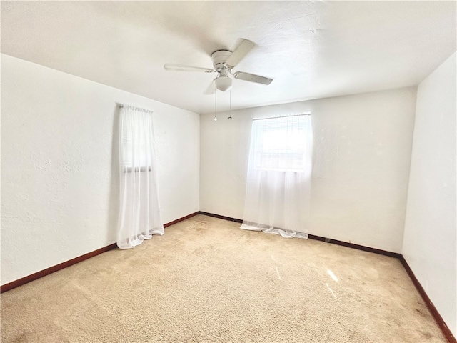 spare room with ceiling fan and light colored carpet