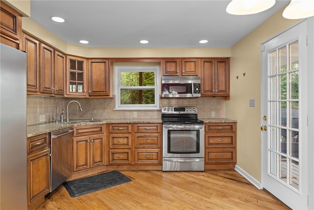 kitchen with light hardwood / wood-style floors, stainless steel appliances, sink, and light stone counters