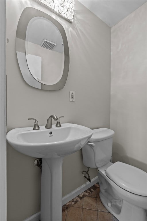 bathroom with toilet, sink, and tile patterned flooring