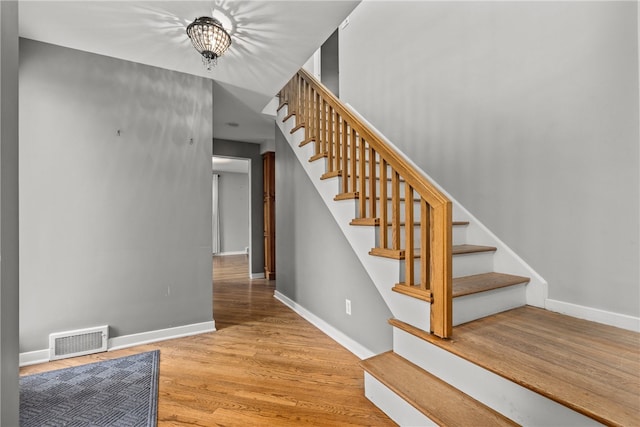 stairs featuring a chandelier and hardwood / wood-style floors