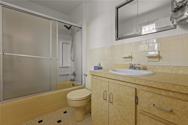 full bathroom featuring bath / shower combo with glass door, tile walls, toilet, vanity, and tile patterned floors