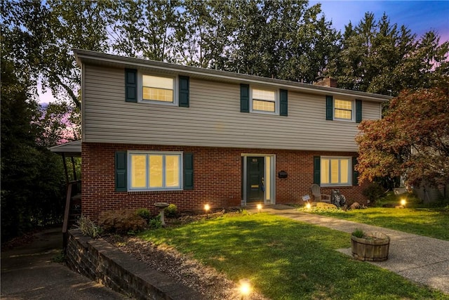 colonial house featuring a front lawn, brick siding, and a chimney