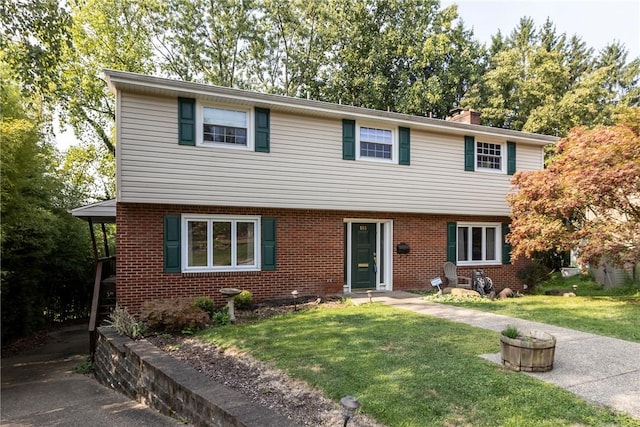 colonial-style house with brick siding, a chimney, and a front lawn