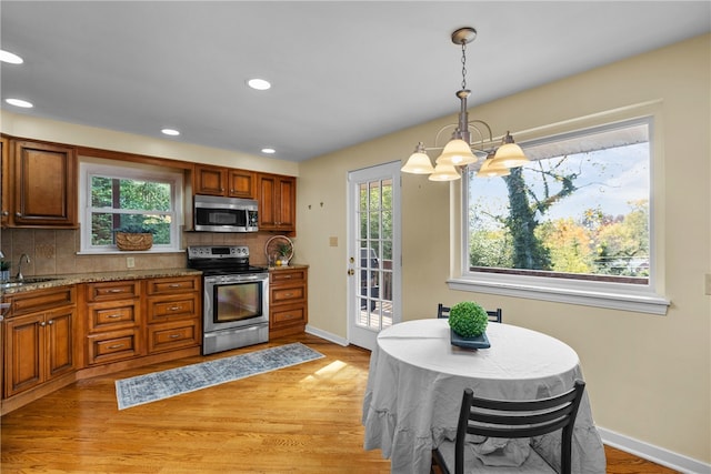 kitchen with backsplash, pendant lighting, stainless steel appliances, and a healthy amount of sunlight