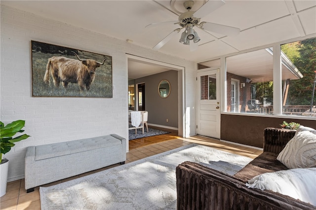 living room with brick wall, light hardwood / wood-style floors, and ceiling fan