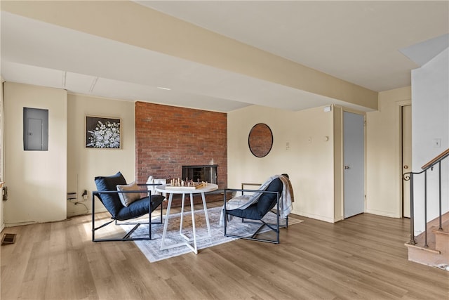 living area featuring electric panel, light hardwood / wood-style flooring, and a fireplace