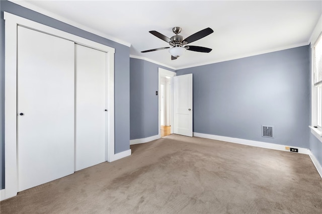 unfurnished bedroom with ornamental molding, light colored carpet, ceiling fan, and a closet