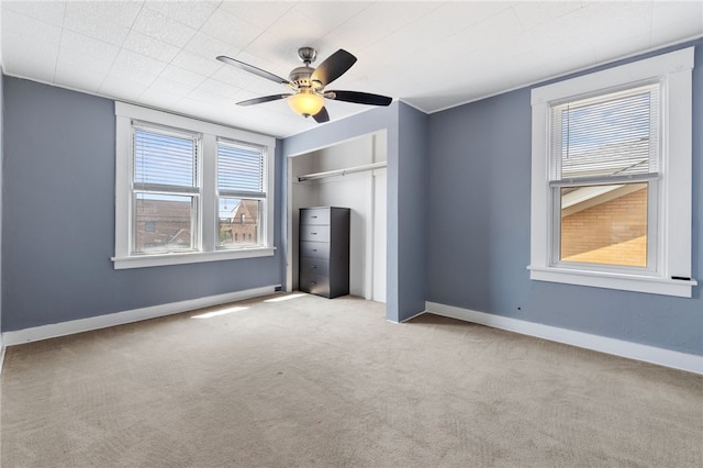 unfurnished bedroom featuring light colored carpet, ceiling fan, and a closet