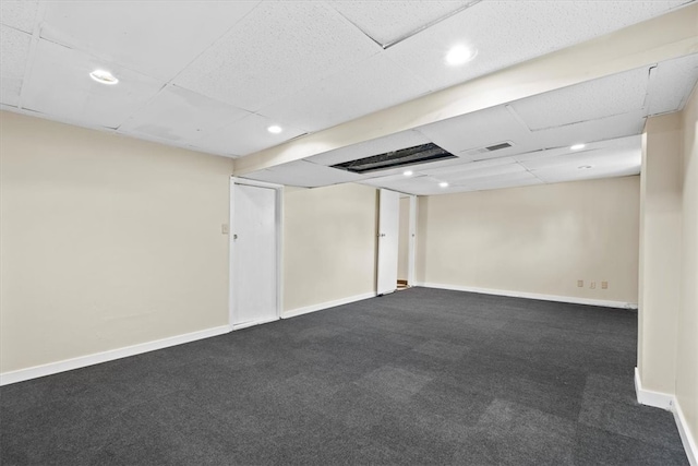 basement featuring dark carpet and a drop ceiling