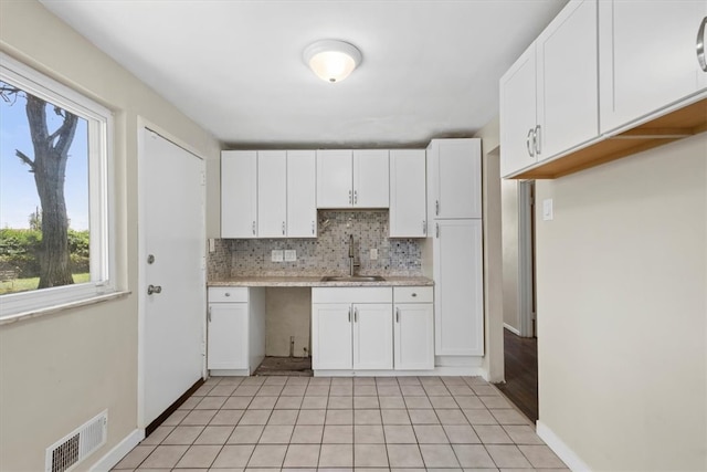 kitchen with sink, white cabinets, decorative backsplash, and light tile patterned floors