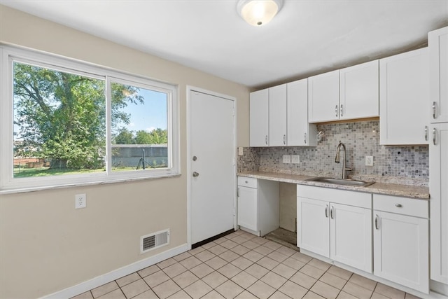 kitchen with light tile patterned flooring, white cabinets, tasteful backsplash, and sink