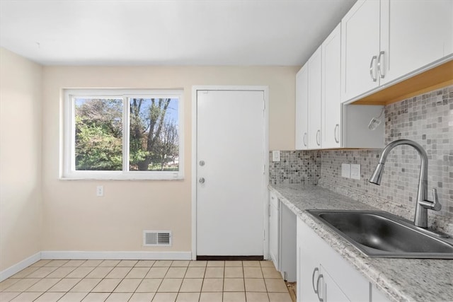 kitchen with backsplash, sink, light tile patterned floors, and white cabinets