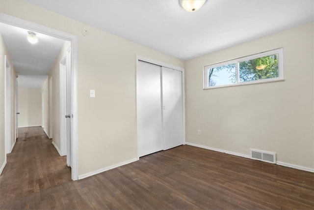 unfurnished bedroom with a closet and dark hardwood / wood-style floors