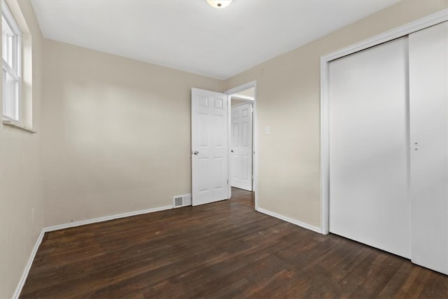 unfurnished bedroom featuring a closet and dark hardwood / wood-style floors