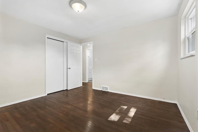 unfurnished bedroom with dark hardwood / wood-style floors and a closet