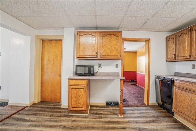 kitchen with black appliances, a drop ceiling, and dark wood-type flooring